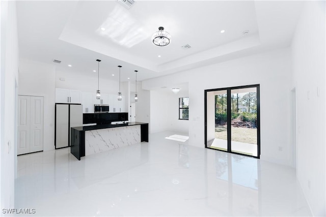 kitchen featuring white cabinetry, stainless steel appliances, a raised ceiling, and hanging light fixtures