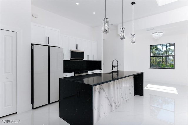 kitchen with sink, white refrigerator, a chandelier, a kitchen island with sink, and white cabinets