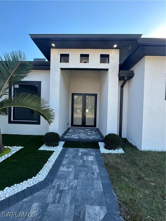 property entrance with a lawn and french doors