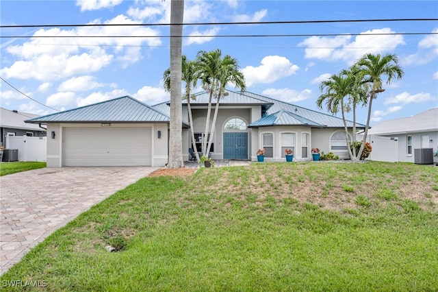 view of front of house featuring central air condition unit, a front yard, and a garage