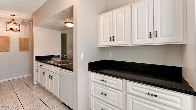 kitchen with white dishwasher, white cabinetry, sink, and a textured ceiling