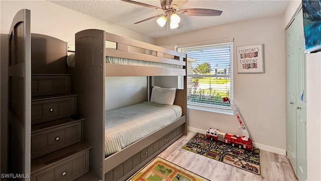 bedroom featuring ceiling fan, light wood-type flooring, and a textured ceiling