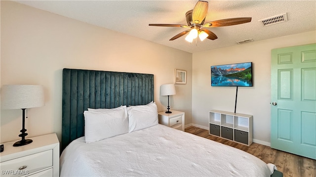 bedroom with ceiling fan, wood-type flooring, and a textured ceiling