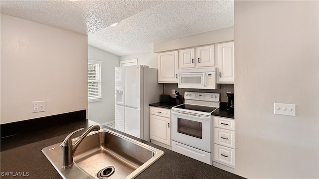 kitchen with a textured ceiling, white appliances, sink, white cabinets, and lofted ceiling