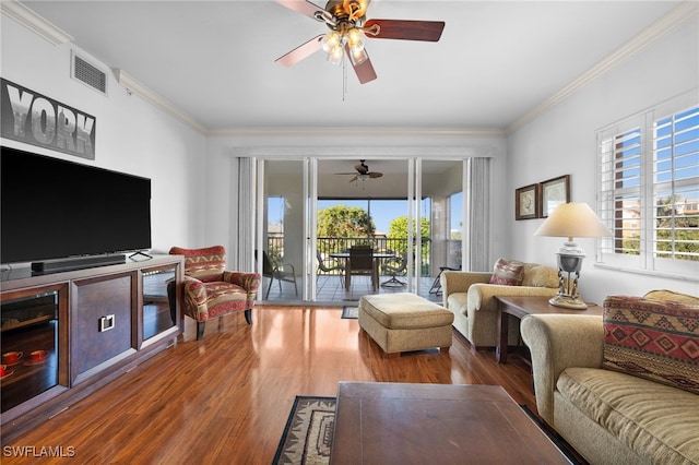 living room with wood-type flooring, plenty of natural light, and ornamental molding