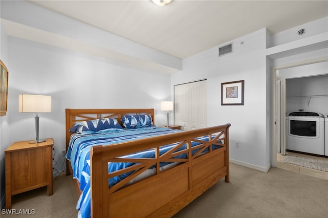 bedroom featuring washer / dryer, light colored carpet, and a closet