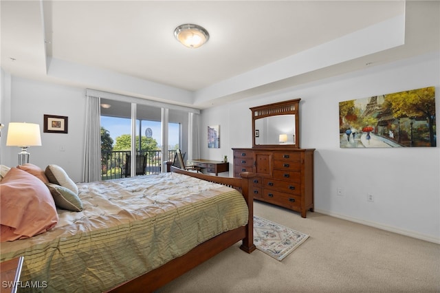 carpeted bedroom featuring access to exterior and a tray ceiling