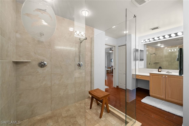 bathroom with vanity, wood-type flooring, a tile shower, and ceiling fan