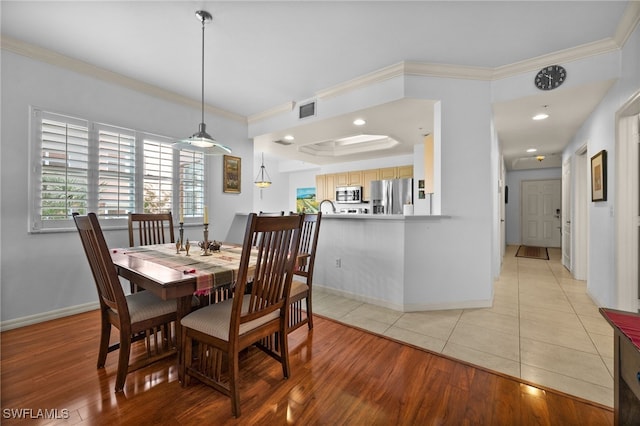 dining area with crown molding and light hardwood / wood-style flooring