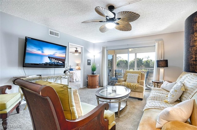 living room with ceiling fan, light colored carpet, and a textured ceiling