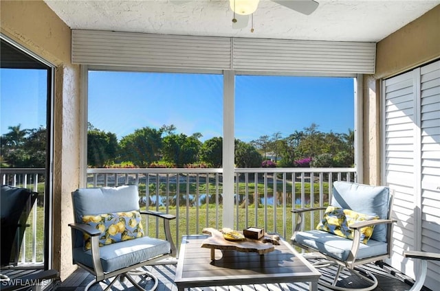 sunroom / solarium featuring a water view and ceiling fan