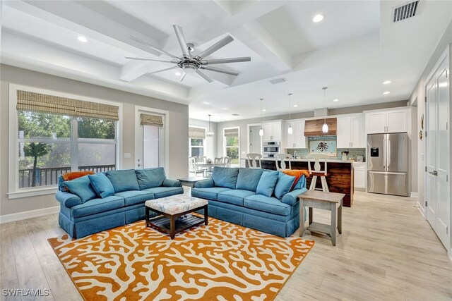 living room featuring coffered ceiling, ceiling fan, beamed ceiling, and light wood-type flooring