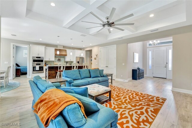 living room featuring ceiling fan with notable chandelier, coffered ceiling, beam ceiling, and light hardwood / wood-style flooring