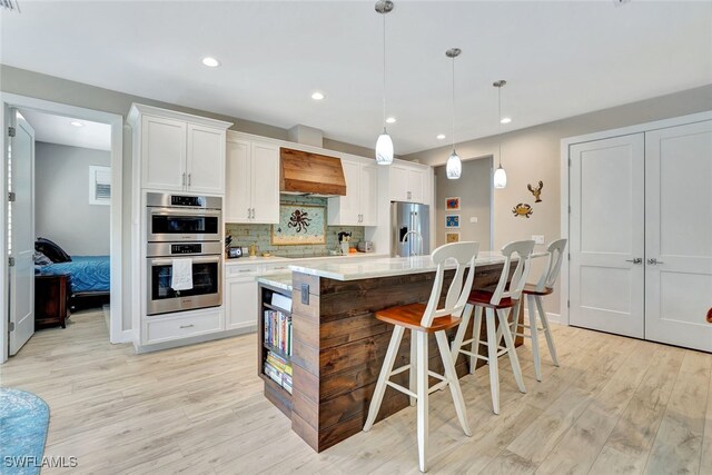 kitchen featuring tasteful backsplash, hanging light fixtures, white cabinets, and a kitchen island