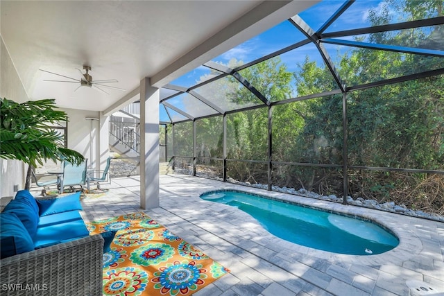 view of pool with ceiling fan, outdoor lounge area, glass enclosure, and a patio area