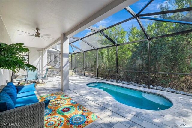 view of pool with a lanai, outdoor lounge area, ceiling fan, and a patio area