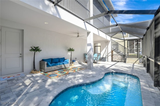 view of swimming pool featuring ceiling fan, a patio area, glass enclosure, and an outdoor living space