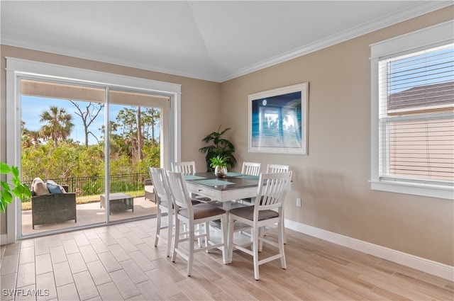 dining space featuring a wealth of natural light, light hardwood / wood-style flooring, vaulted ceiling, and ornamental molding