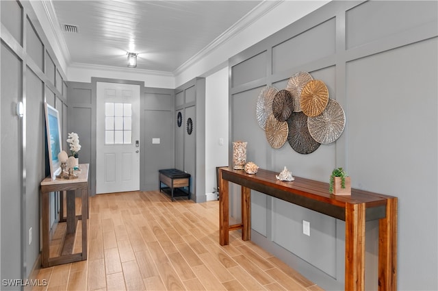 entryway with light hardwood / wood-style floors and crown molding