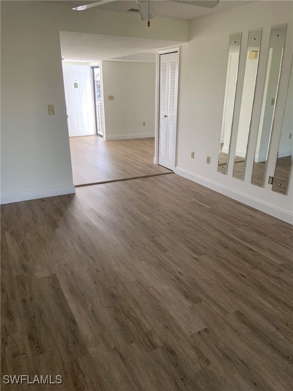 empty room with ceiling fan and dark hardwood / wood-style flooring