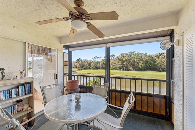 sunroom featuring a water view and ceiling fan