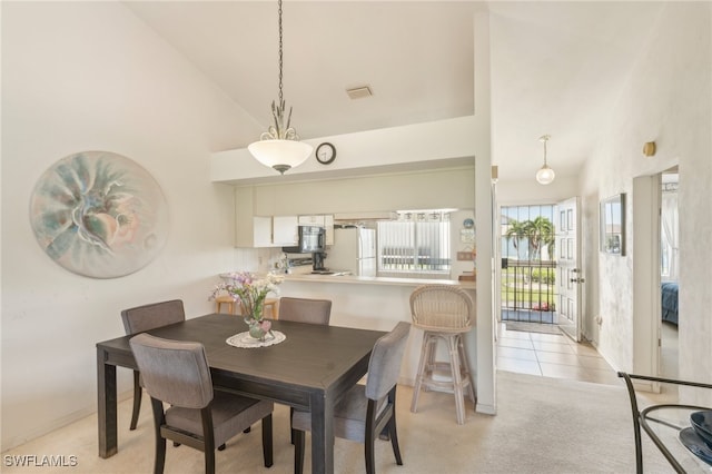 carpeted dining area featuring high vaulted ceiling