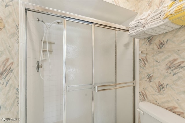 bathroom featuring a shower with shower door and toilet