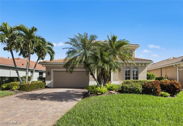 view of front facade with a garage, decorative driveway, a tiled roof, and stucco siding