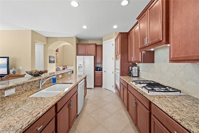 kitchen featuring white appliances, sink, light tile patterned floors, tasteful backsplash, and light stone counters