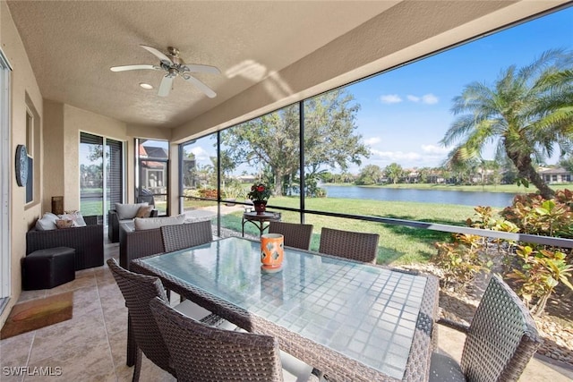 sunroom with ceiling fan and a water view