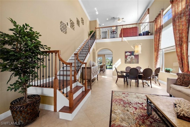 interior space with light tile patterned floors, a towering ceiling, and ceiling fan