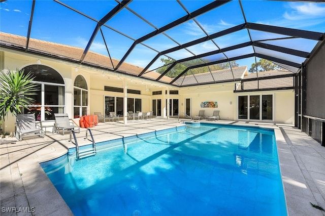 view of pool with glass enclosure, ceiling fan, and a patio area