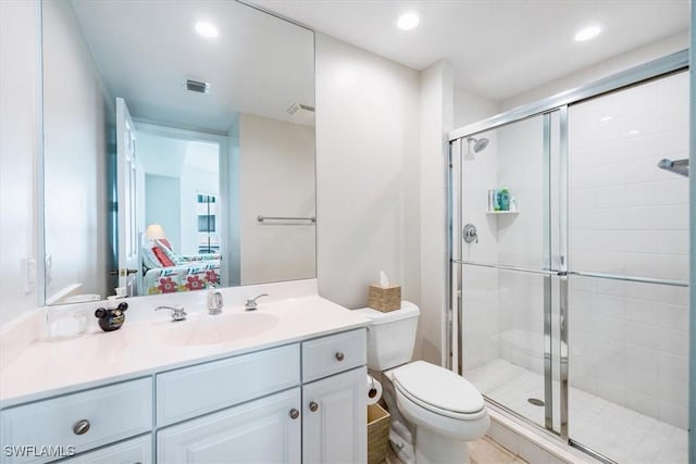 bathroom with vanity, toilet, and a shower with door