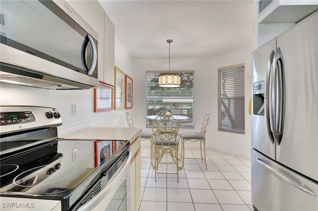 kitchen featuring pendant lighting, light tile patterned floors, and stainless steel appliances