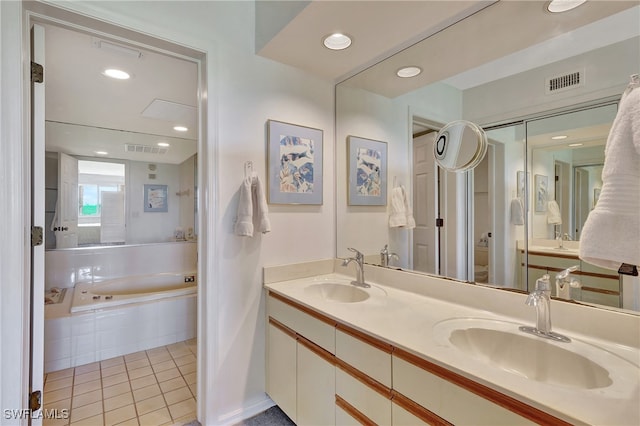 bathroom with tile patterned flooring, vanity, and tiled tub