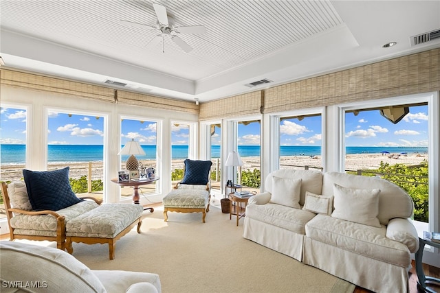 sunroom with a view of the beach, a water view, a wealth of natural light, and ceiling fan