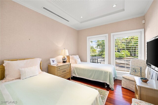 bedroom featuring dark hardwood / wood-style floors, a raised ceiling, and crown molding