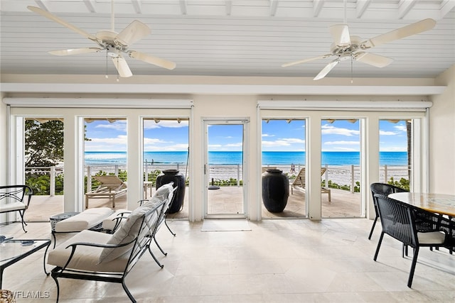 sunroom / solarium featuring a water view, a healthy amount of sunlight, and a beach view