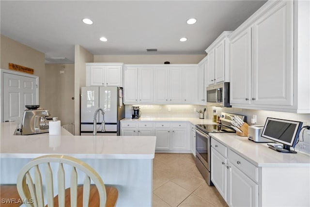 kitchen featuring decorative backsplash, appliances with stainless steel finishes, light tile patterned floors, and white cabinetry