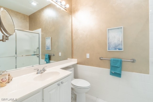 bathroom with tile patterned floors, an enclosed shower, toilet, vanity, and tile walls