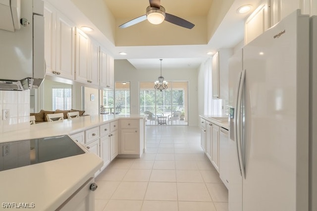 kitchen featuring kitchen peninsula, white appliances, a healthy amount of sunlight, decorative light fixtures, and white cabinets