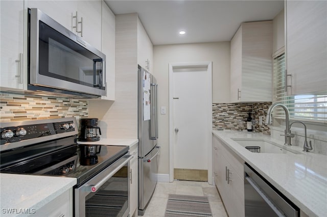 kitchen featuring backsplash, sink, light tile patterned floors, light stone counters, and stainless steel appliances