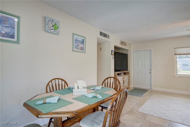 dining space with light tile patterned floors and a textured ceiling