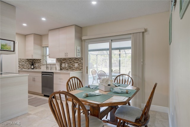 dining area with sink, a textured ceiling, and light tile patterned flooring