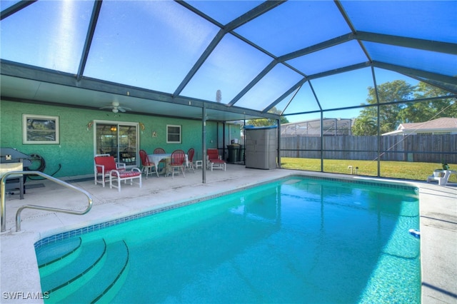 view of pool with glass enclosure, a patio area, a yard, and ceiling fan