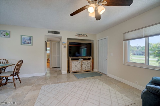 living room featuring a textured ceiling and ceiling fan