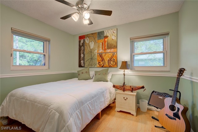 bedroom with multiple windows, ceiling fan, light hardwood / wood-style floors, and a textured ceiling