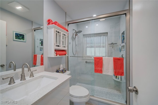 bathroom with vanity, toilet, and a shower with door