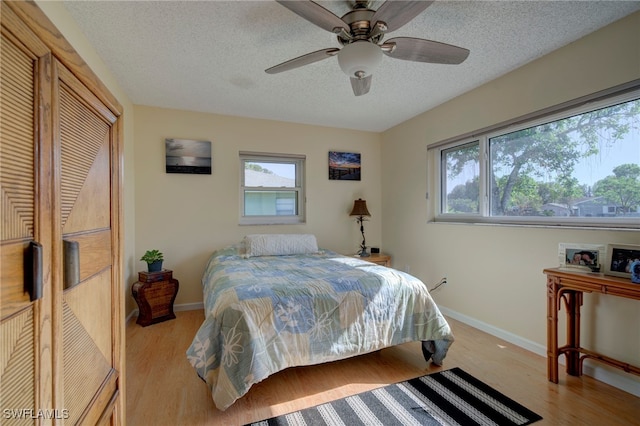 bedroom with ceiling fan, light hardwood / wood-style flooring, and a textured ceiling