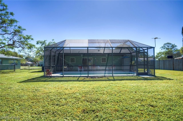 back of property featuring a lawn, glass enclosure, and a swimming pool